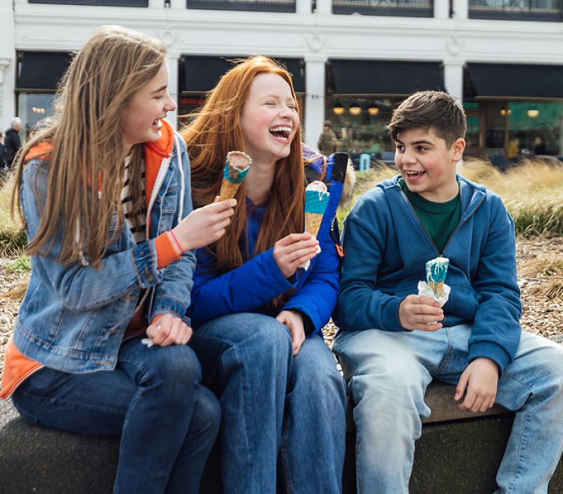 three children enjoying ice cream on the seafront